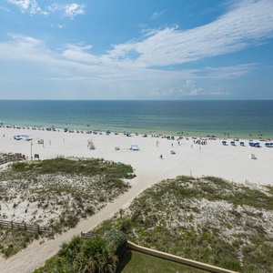 Breathtaking beachfront view showcasing white sand, beachgoers, and colorful umbrellas under a clear blue sky