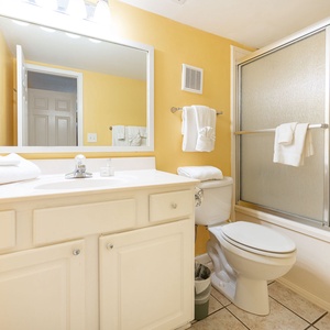 Bright and welcoming master bathroom featuring a large mirror, white towels, and a glass-enclosed shower