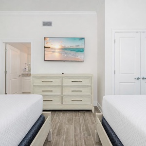 Relax in this comfortable guest bedroom featuring two queen beds, a stylish dresser, and a TV