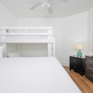 Bright and airy guest bedroom featuring a cozy queen bed, twin bunk bed, and a TV for entertainment