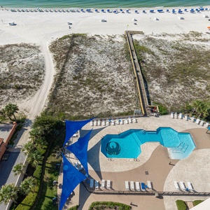 Relax by the inviting pool area surrounded by lounge chairs and lush landscaping, just steps from the beach