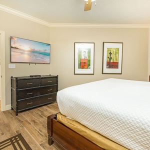 Retreat to this serene master bedroom featuring a plush king bed, stylish decor, and a large TV for your entertainment
