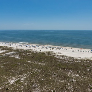 Expansive view of the beach with colorful umbrellas lining the shore and gentle waves lapping against the white sand