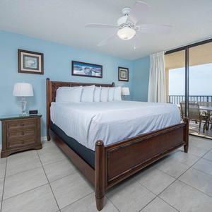 Bright blue walls complement the king bed in this inviting master bedroom, featuring a balcony with a view of the beach