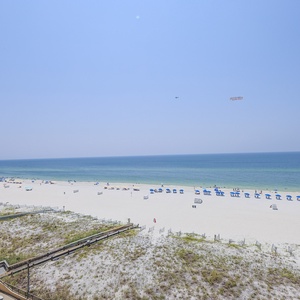 Serene view showcases a pristine beach with white sand and blue umbrellas, inviting relaxation under a clear sky