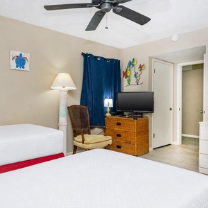 This guest bedroom features two beds, a TV, and colorful decor, creating a cheerful and relaxing atmosphere