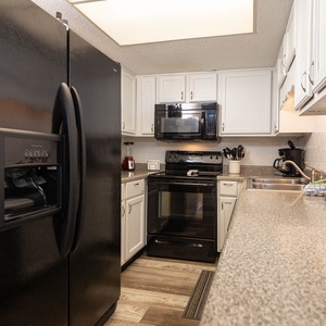 Modern kitchen featuring sleek black appliances, granite countertops, and ample storage for a delightful cooking experience
