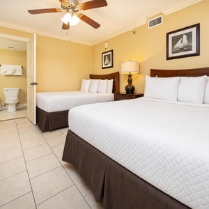 Brightly colored walls complement two double beds, a lamp, and artwork, creating a welcoming vibe in the guest bedroom