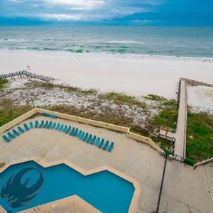 Enjoy the inviting poolside view with lounge chairs and a scenic path leading to the pristine serene beach