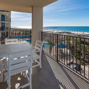 Enjoy coastal views from your balcony while relaxing at the white table, sipping your favorite drink