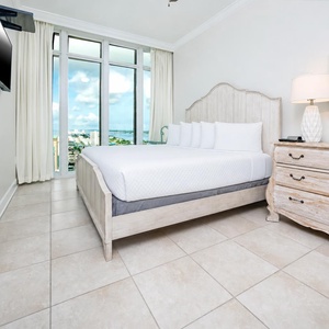 Serene guest bedroom featuring a king bed, stylish decor, and large windows offering beautiful beach views