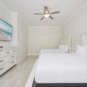 Inviting guest bedroom featuring two comfortable queen beds and a large TV