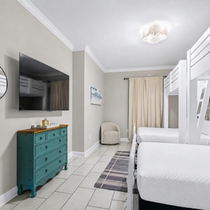 Inviting guest room featuring two queen beds, two twin loft bunk beds, large TV, and a cozy vibe
