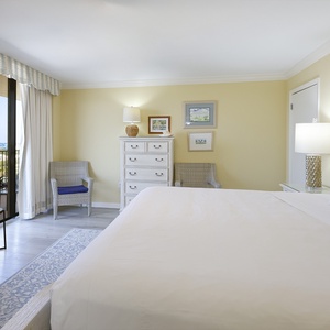 Bright yellow walls complement the inviting king bed in the master, with a cozy seating area and balcony access