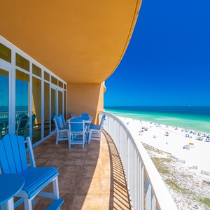 Blue chairs surround tables where you listen to waves and watch the beach unfold from your balcony