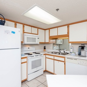 The kitchen area featuring white cabinetry, a sleek countertop, and a coffee station for convenient morning brews
