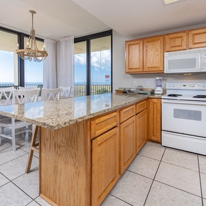 Kitchen featuring a spacious breakfast bar, wooden cabinetry, white appliances, and stunning views of the beach