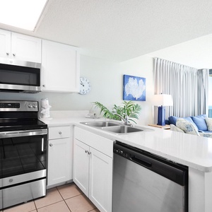 Cook meals in this sleek kitchen, featuring stainless steel appliances and a beachfront view