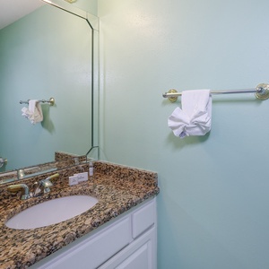 Vibrant aqua walls complement the granite countertop and mirror in this inviting additional half bathroom