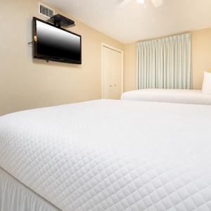 Relax in this inviting guest bedroom featuring two comfortable double beds and a TV during your stay