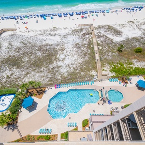 Take a refreshing dip in the inviting pool surrounded by lounge chairs and lush landscaping, just steps from the beach