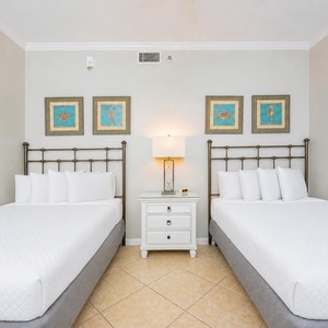 Relax in the cozy guest bedroom with plush full beds and vibrant artwork, perfect for restful nights after a beach day