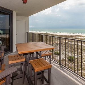 Balcony patio set offers a view of the beach, inviting relaxation and gulf breezes