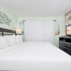 White curtains draw a quiet calm as you settle into the king suite with a restful, plush bed