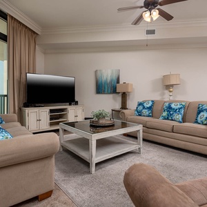 The living area features a large TV, comfortable seating with vibrant blue accents, and a welcoming atmosphere for relaxation