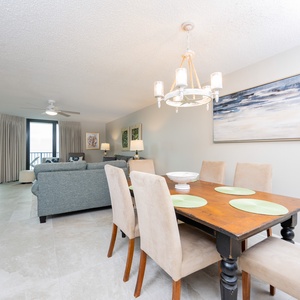 Dining area features a charming wooden table with green placemats, surrounded by plush chairs