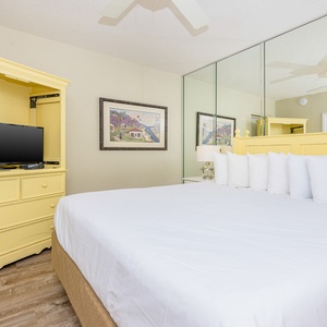 Relax in the bright bedroom featuring a king bed, a TV, and charming yellow decor for a cheerful atmosphere