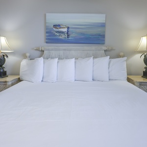 Cozy master bedroom featuring a large king bed, flanked by stylish lamps and a serene boat painting above the headboard