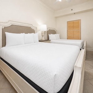 Two comfortable queen beds and a stylish lamp create a serene atmosphere in this inviting guest room