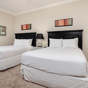 This bedroom features two comfortable queen beds, stylish black furniture, and colorful artwork for a cheerful atmosphere