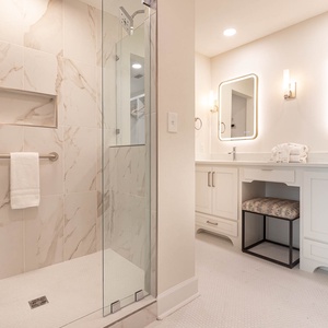 The master bath features a stylish walk-in shower with elegant marble tiles and dual vanities for a luxurious experience