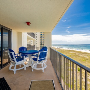 Balcony with blue adirondack chairs and table offers a relaxing spot to enjoy the beach front and gulf views