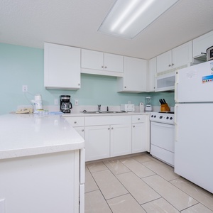 Spacious full kitchen featuring white cabinets, large and small appliances, and a convenient breakfast bar