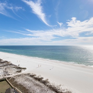 A stunning beachfront view showcases the shimmering water and white sand, inviting relaxation and seaside enjoyment