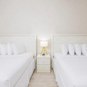 In the guest suite with two queen beds, unwind under a glowing lamp after a day of coastal fun