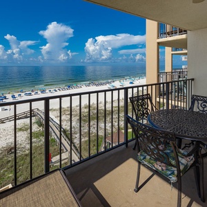 Relax on the balcony with a table and chairs, enjoying the beautiful beach view just steps away from your retreat