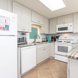 Bright kitchen features sleek cabinetry, a breakfast bar, and white appliances, creating an inviting space