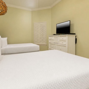 This cozy guest bedroom features two full beds, a TV for entertainment, and a stylish woven light fixture