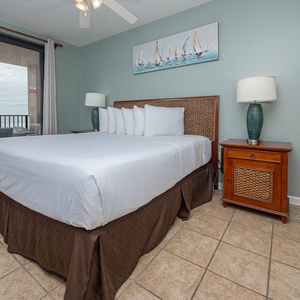 Relax in the master bedroom featuring a comfortable king bed, coastal decor, and easy access to the beachfront balcony