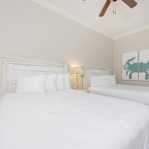 Guest bedroom featuring two cozy full beds, a charming crab artwork, and soft, neutral decor for a relaxing stay