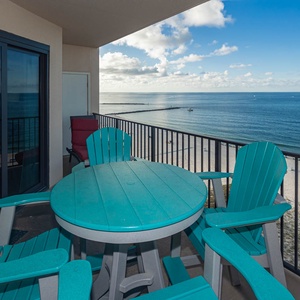 Relax at the outdoor table with colorful chairs, enjoying expansive views of tranquil waters and the coastline
