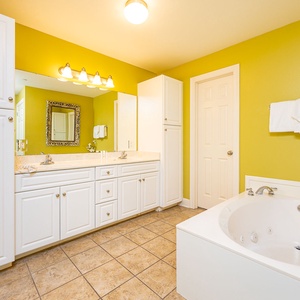 Bathe in the whirlpool tub while white towels and floral accents add a fresh, calm touch to this master bath