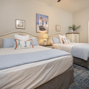 Rest in this tranquil guest bedroom with two queen beds, coastal decor, and soft lighting for a restful retreat