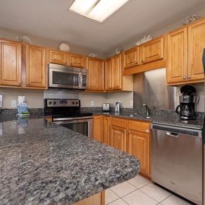 Granite countertops complement the wooden cabinetry in this modern kitchen, featuring a coffee maker and stainless appliances