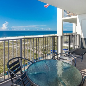 Balcony with a glass table and chairs offers a serene view of the beach and gulf, perfect for relaxing moments