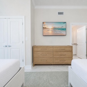 Enjoy restful nights in this inviting guest room featuring two comfortable beds, a stylish dresser, and a large TV